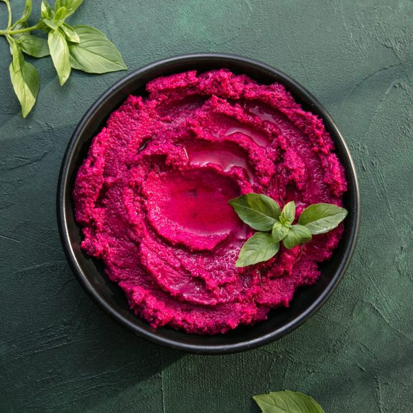 Hummus plate. Beetroot hummus with fresh vegetables, olive oil, and a dark background.