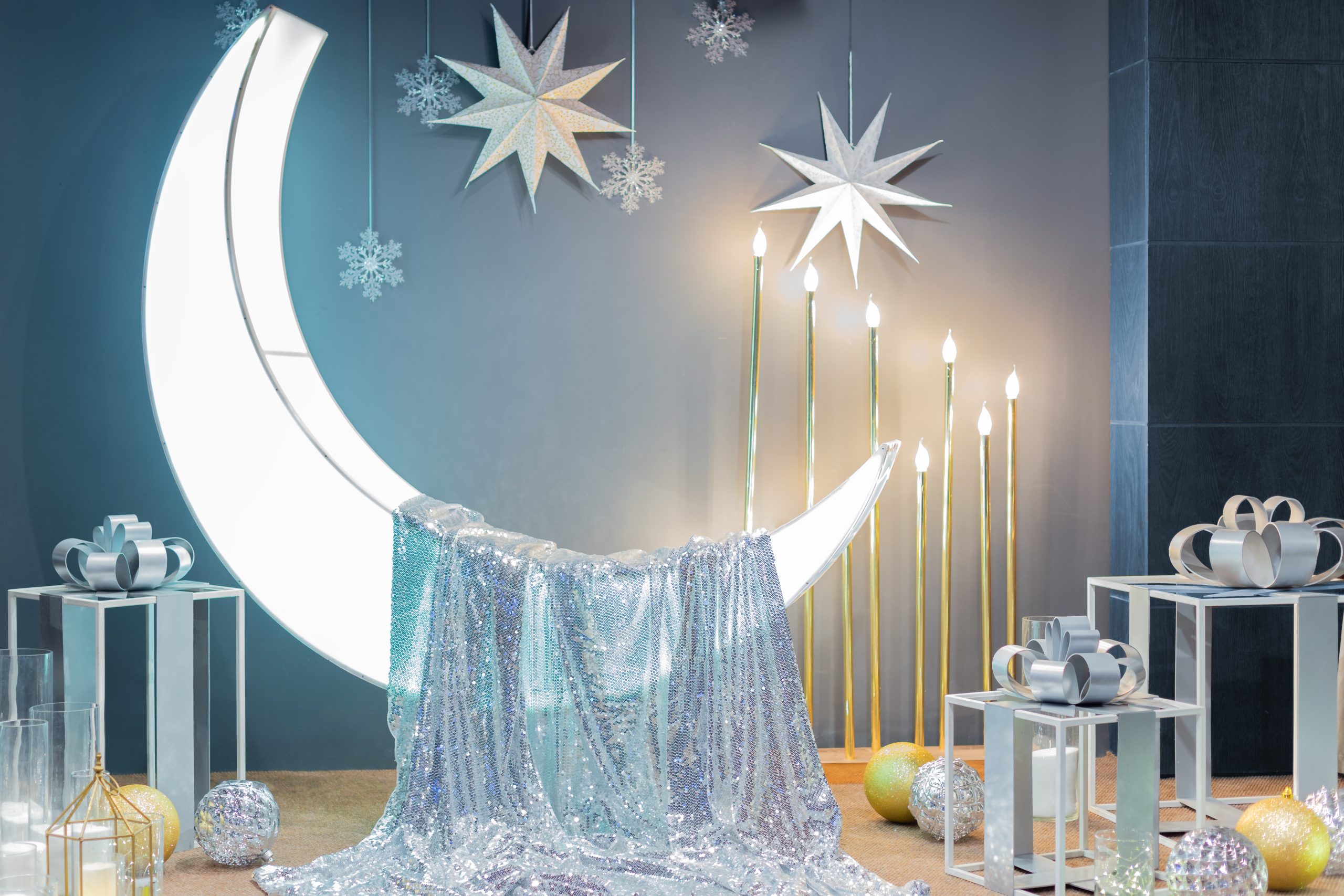 Photo zone in a restaurant celebrating a wedding, birthday, anniversary. A month with silver shiny fabric on which you can sit, snowflakes and stars on the wall, gifts and balls on the floor, decorations